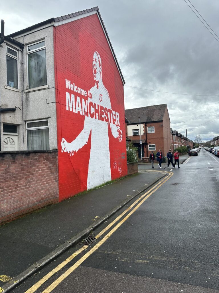 Wandbild mit dem Schriftzug Welcome to Manchester in einer Straße bei Old Trafford